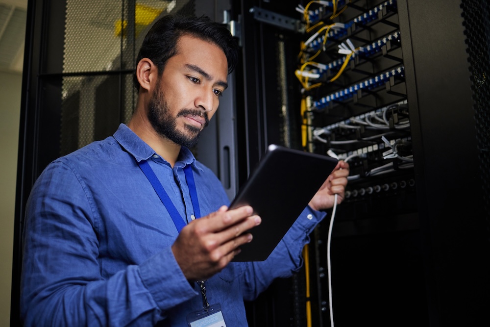 Server room, tablet and engineer with connection cable for IT maintenance or software update at night.